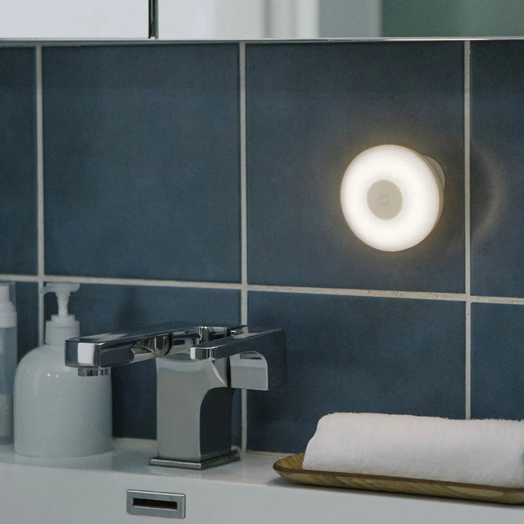 White modern bedside table lamp with human body induction and Bluetooth on a wooden nightstand.