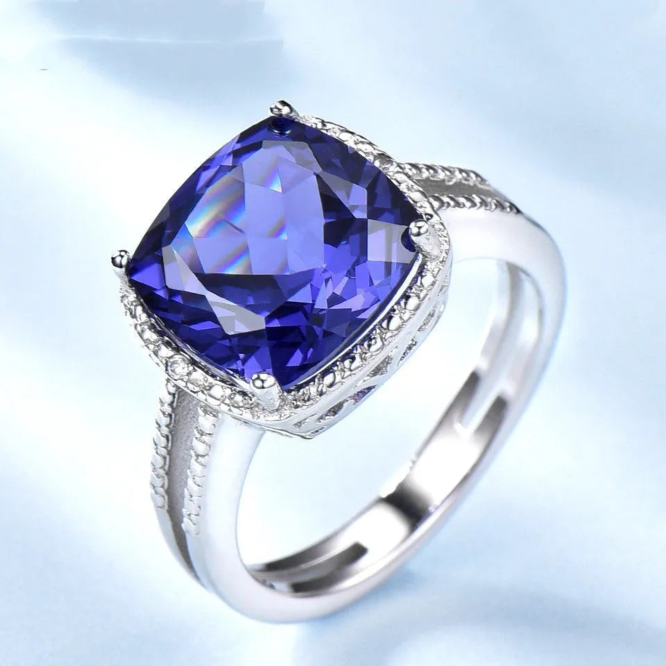 Blue tanzanite gemstone set in a sterling silver women's ring on a grey background