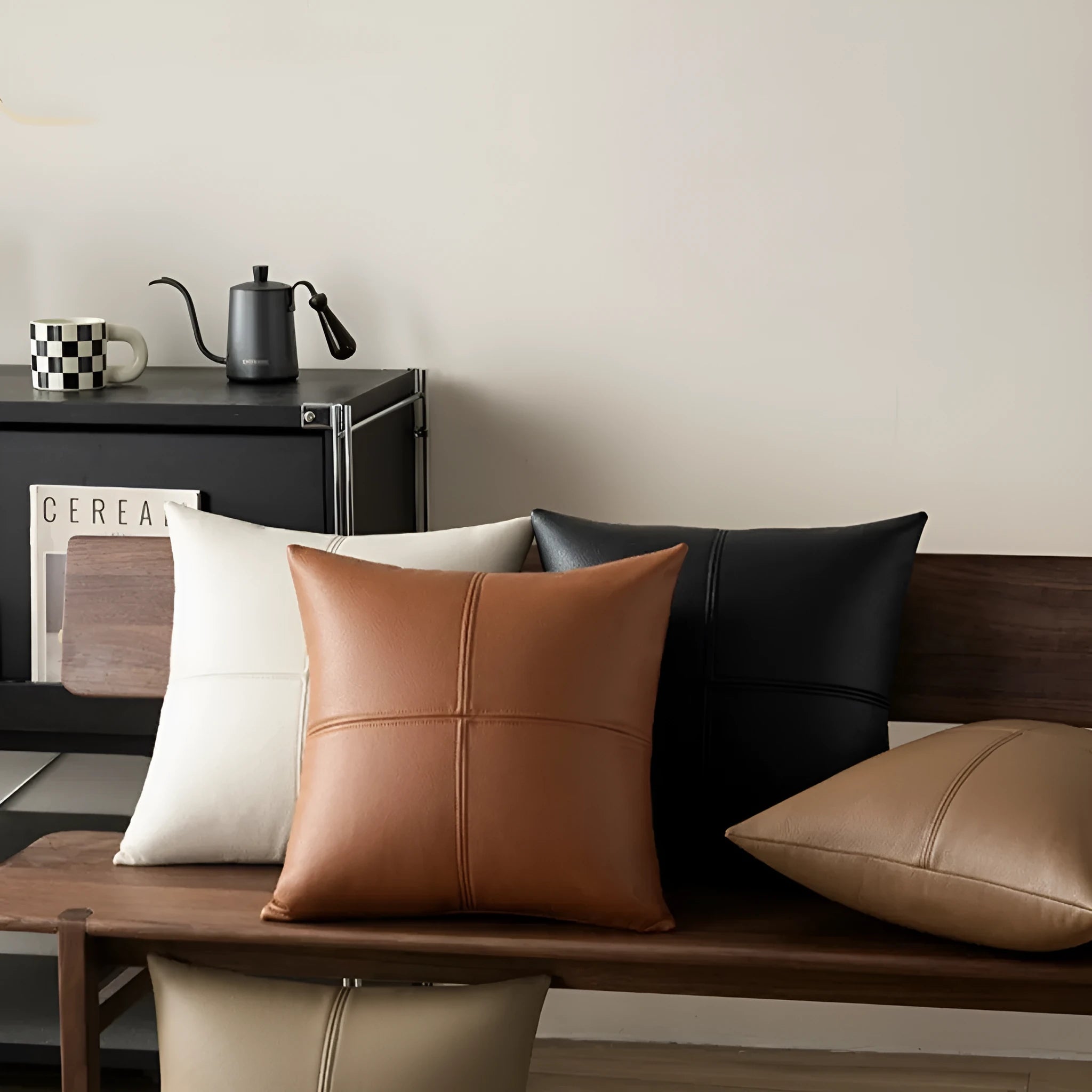 Solid colour cowhide leather pillow cover in brown on a grey sofa, shown in a square shape.