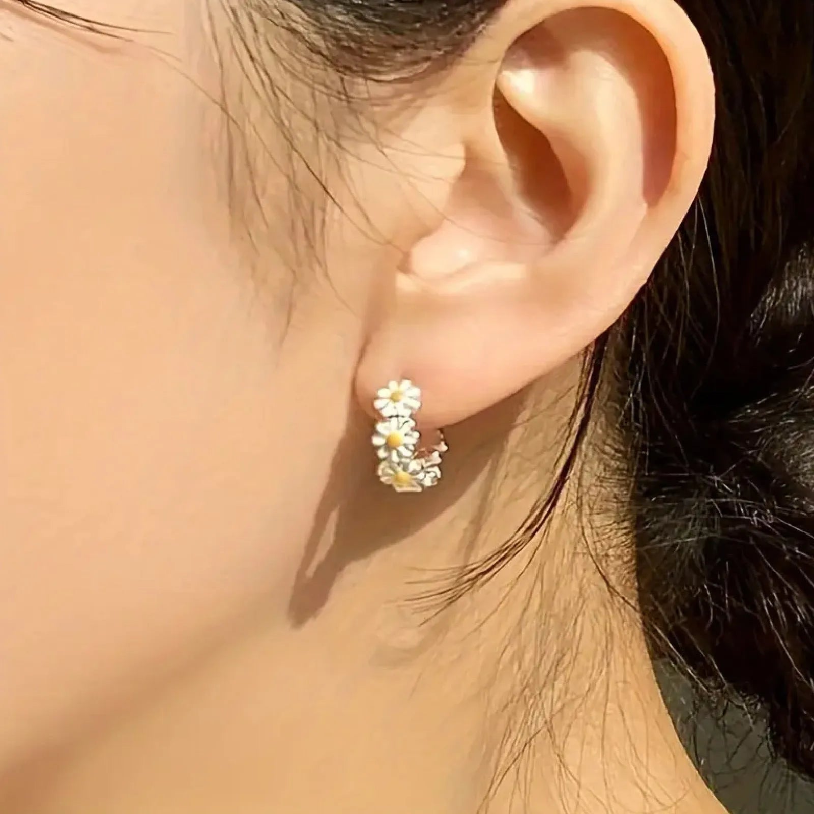 A pair of white daisy flower ring earrings with inlaid gems, shown on a plain background.