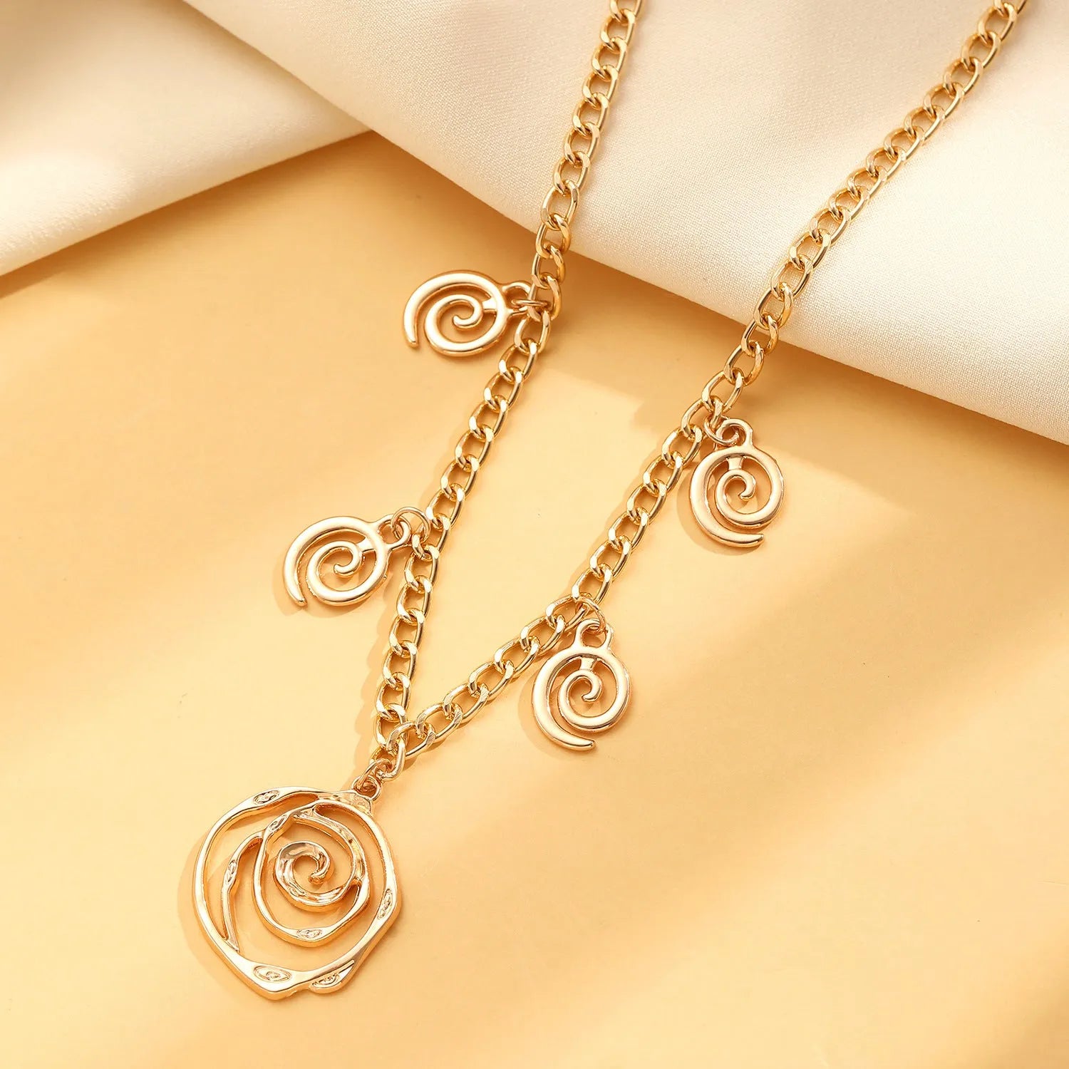 Gold and silver spiral donut pendant necklace, bracelet, and earrings set for women.