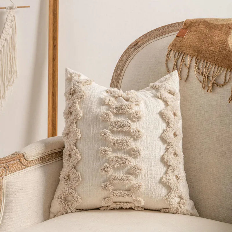 Knitted pillow cover with tassel trim in a spiral dot pattern on a striped background.