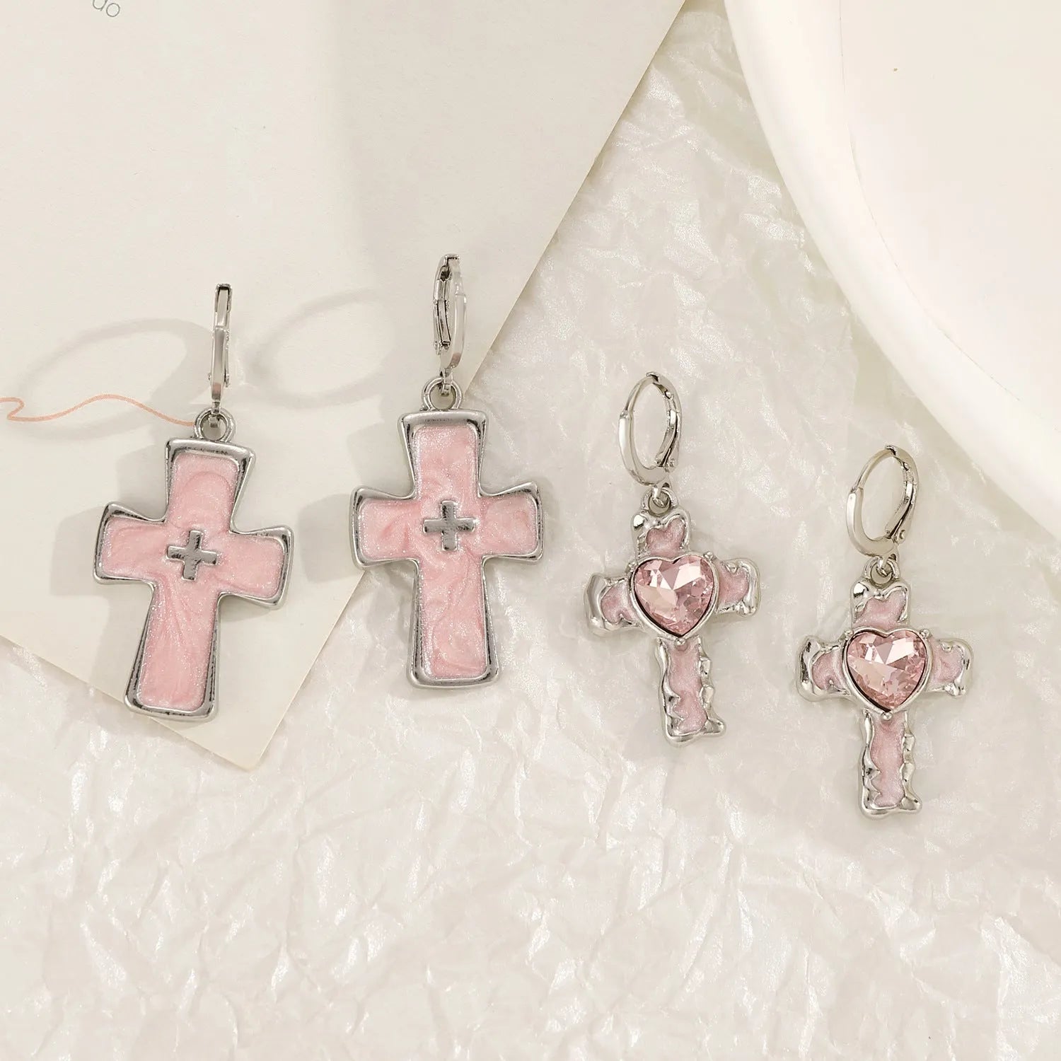 Women's alloy earrings showing cross, heart, and animal designs in white, black, and silver colour variations