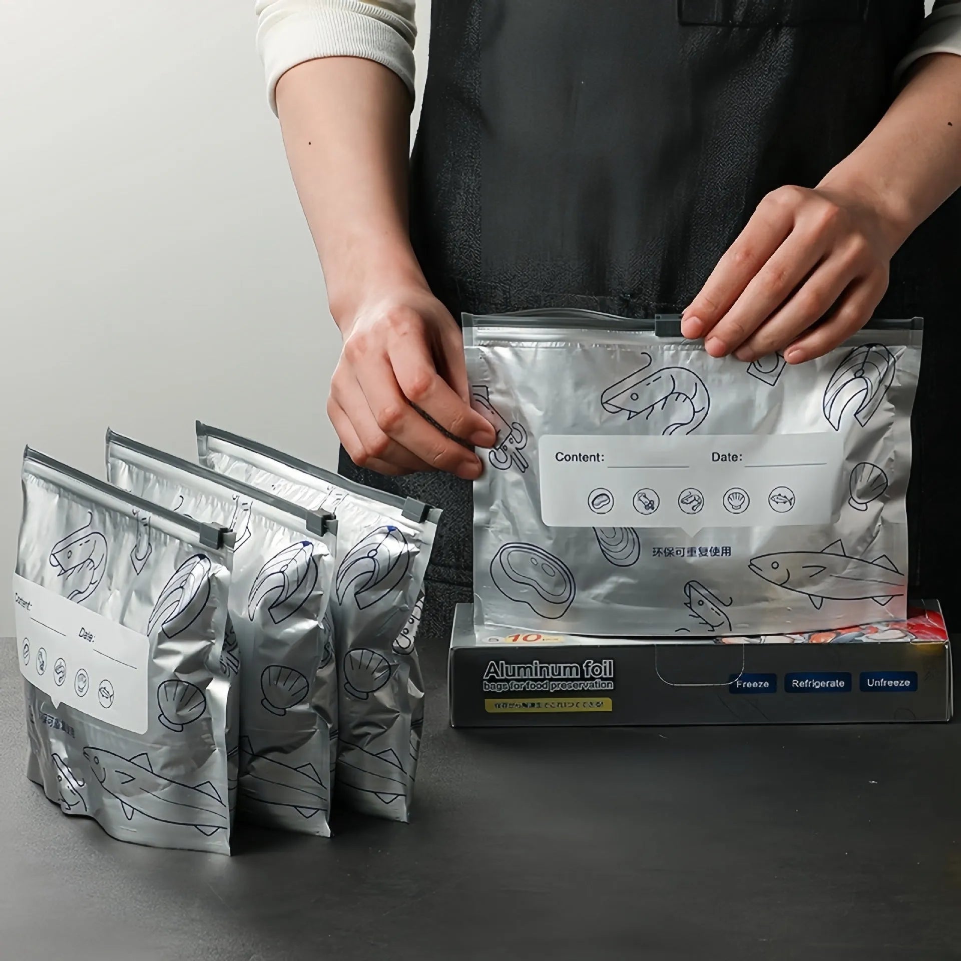 Set of resealable aluminium foil fresh-keeping bags in small, medium, and large sizes on a kitchen counter.