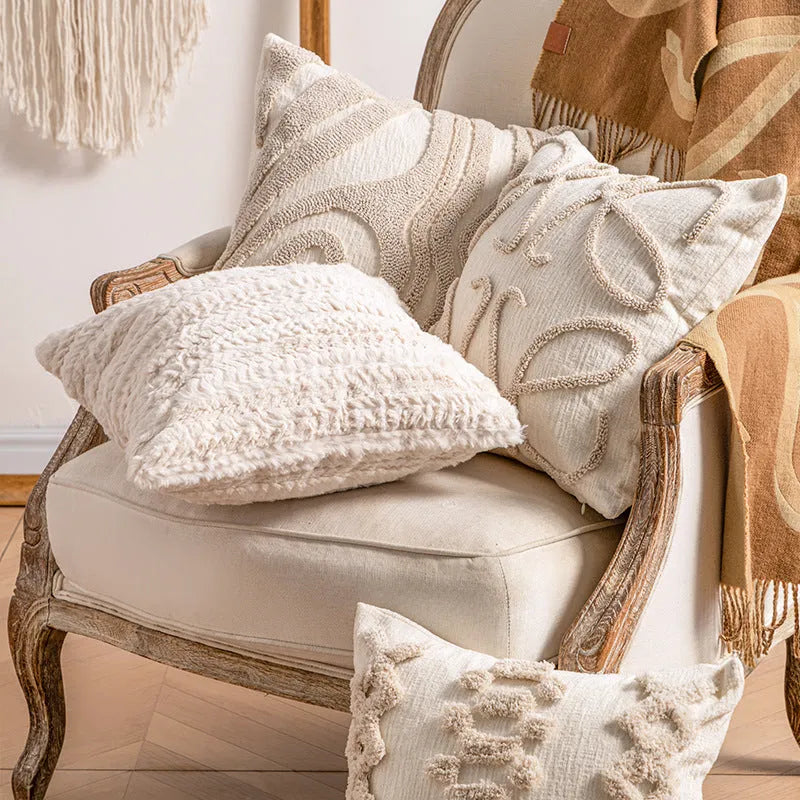 Knitted pillow cover with tassel trim in a spiral dot pattern on a striped background.