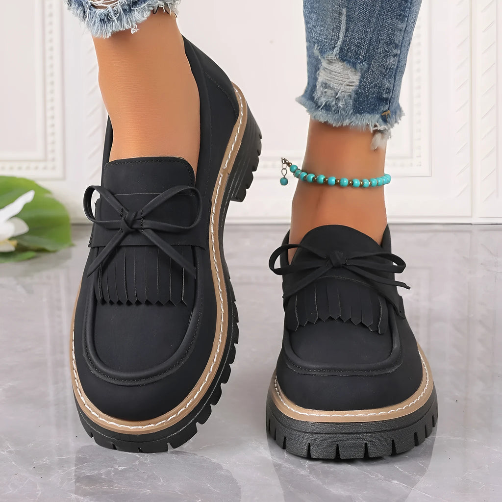 Women's black plus size slip-on loafers with tassel detail and a thick chunky heel.