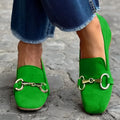 Green suede women's loafers with a round toe and silver metal buckle fastener on a flat rubber sole.