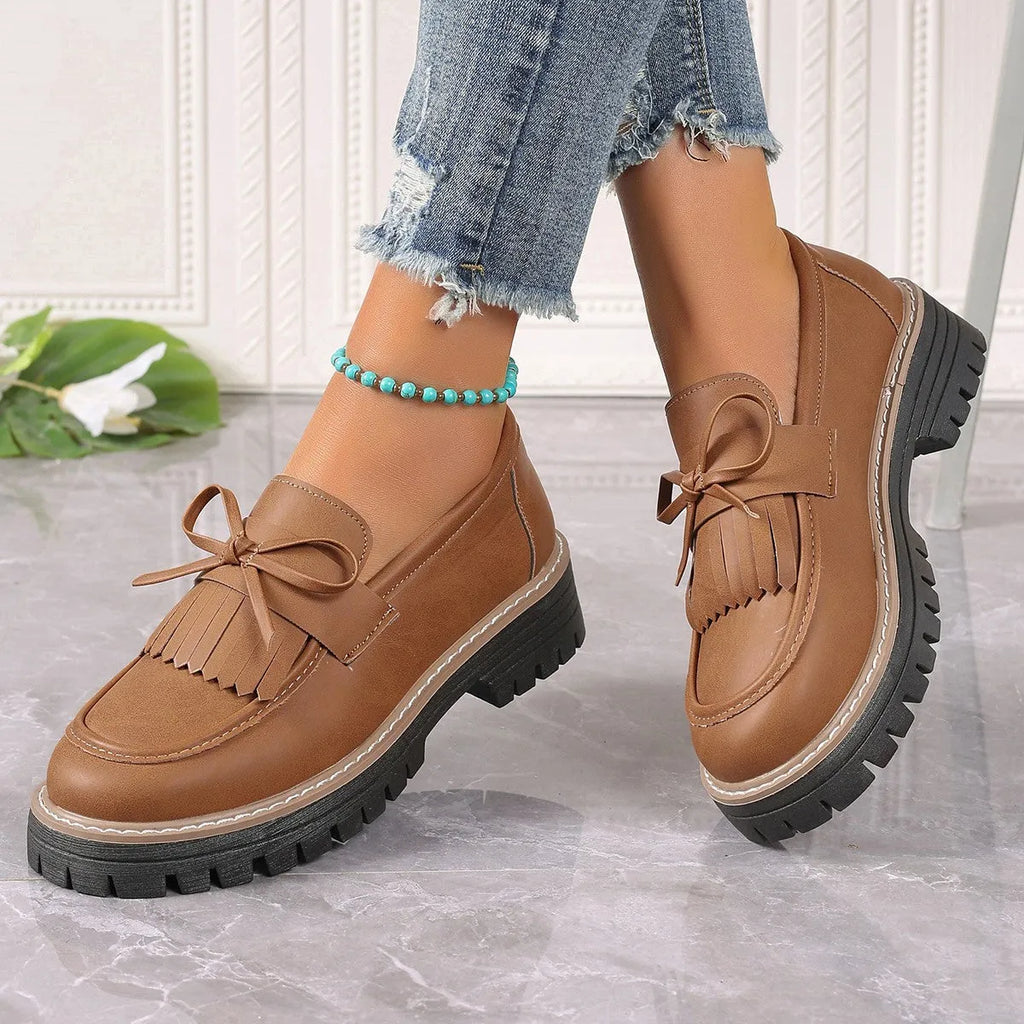 Women's black plus size slip-on loafers with tassel detail and a thick chunky heel.