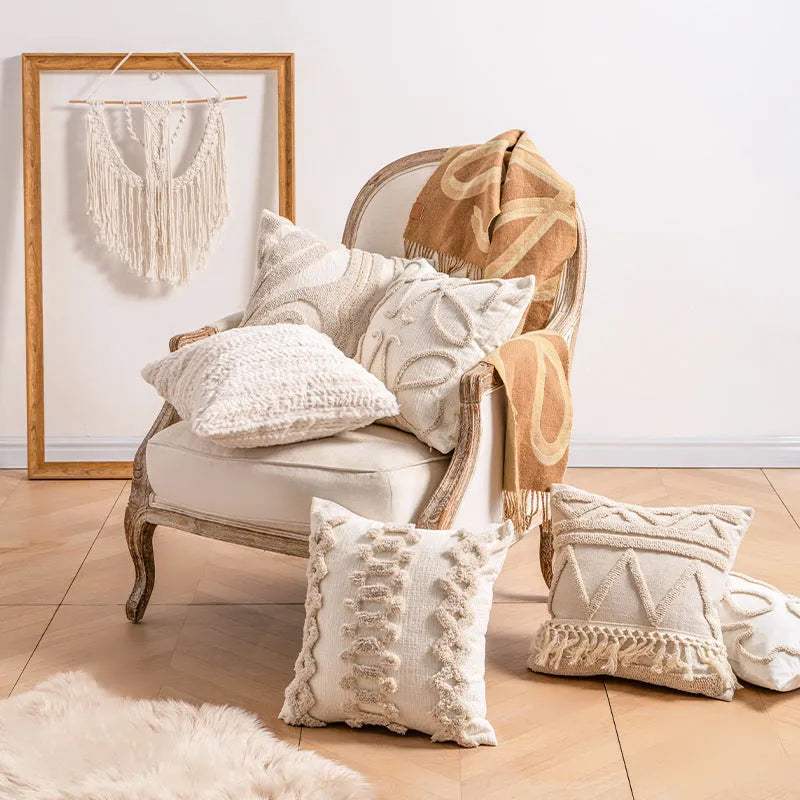 Knitted pillow cover with tassel trim in a spiral dot pattern on a striped background.