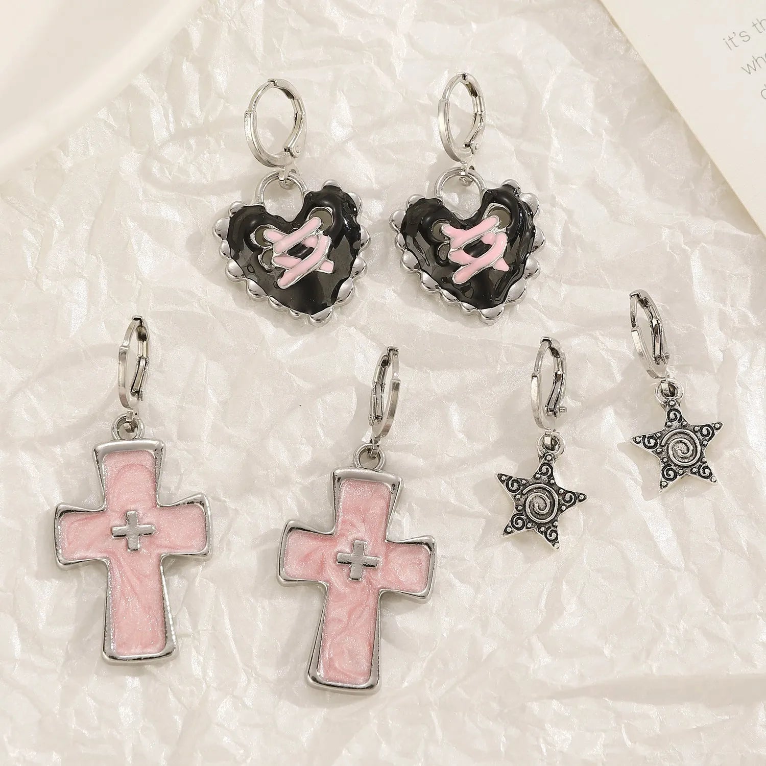 Women's alloy earrings showing cross, heart, and animal designs in white, black, and silver colour variations