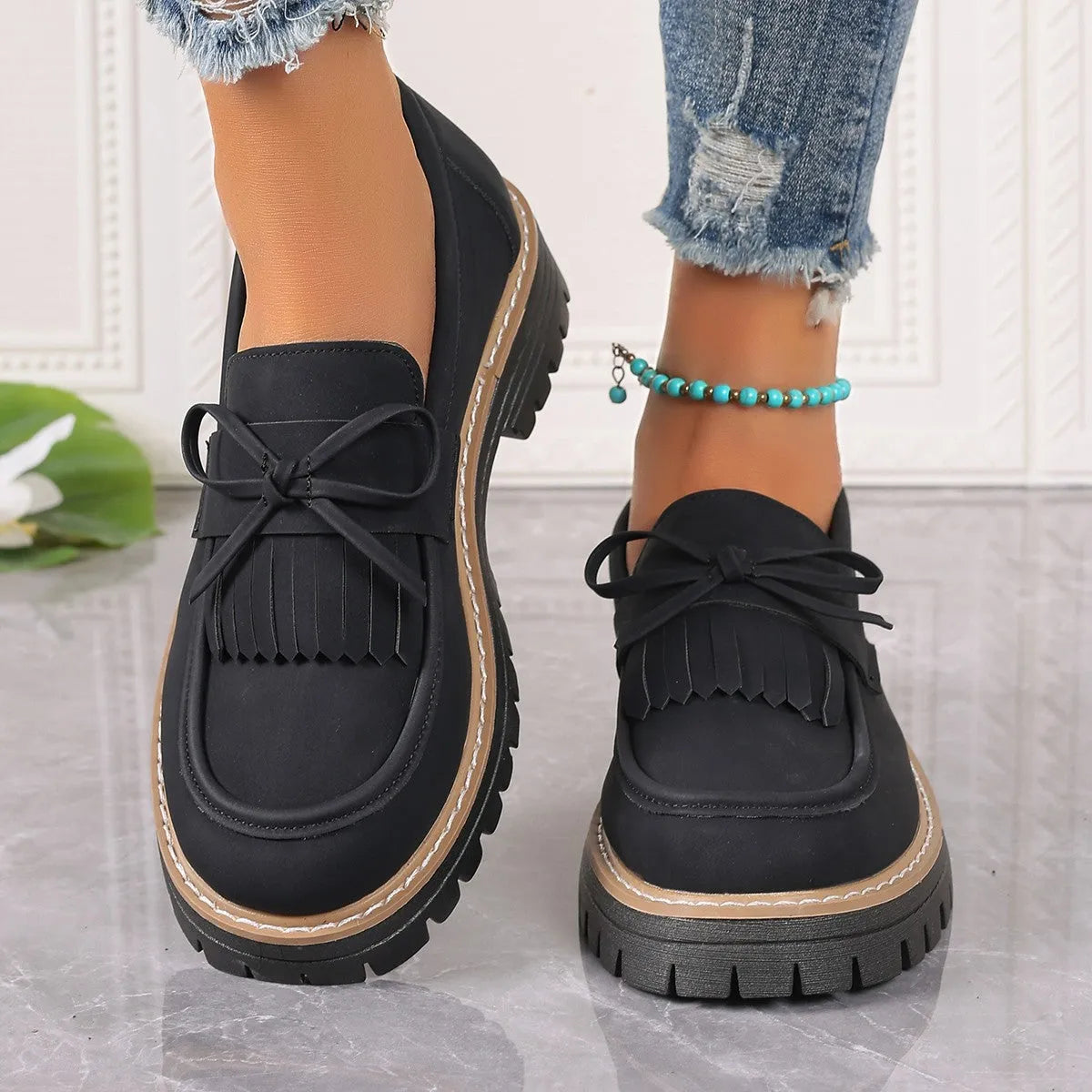 Women's black plus size slip-on loafers with tassel detail and a thick chunky heel.