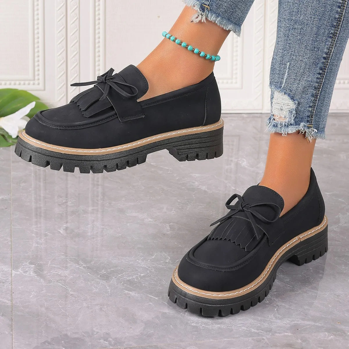 Women's black plus size slip-on loafers with tassel detail and a thick chunky heel.