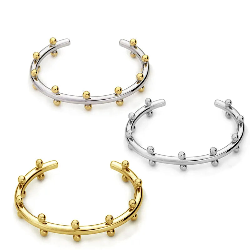 Stainless steel C-shaped bracelet with rivet-shaped bean beads in a steel-gold colour finish.