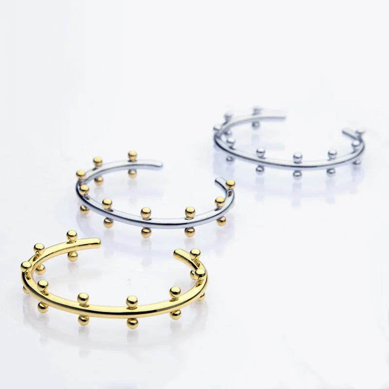 Stainless steel C-shaped bracelet with rivet-shaped bean beads in a steel-gold colour finish.