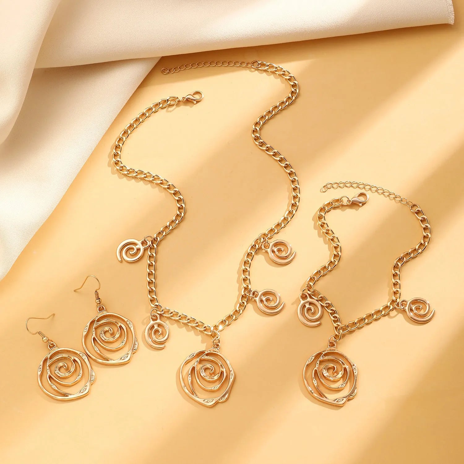 Gold and silver spiral donut pendant necklace, bracelet, and earrings set for women.