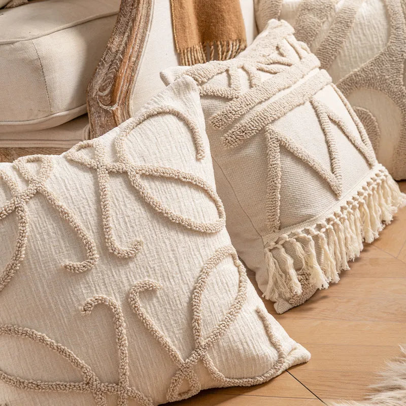Knitted pillow cover with tassel trim in a spiral dot pattern on a striped background.