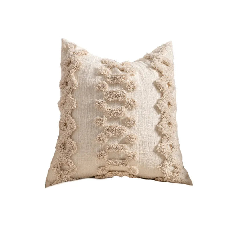 Knitted pillow cover with tassel trim in a spiral dot pattern on a striped background.