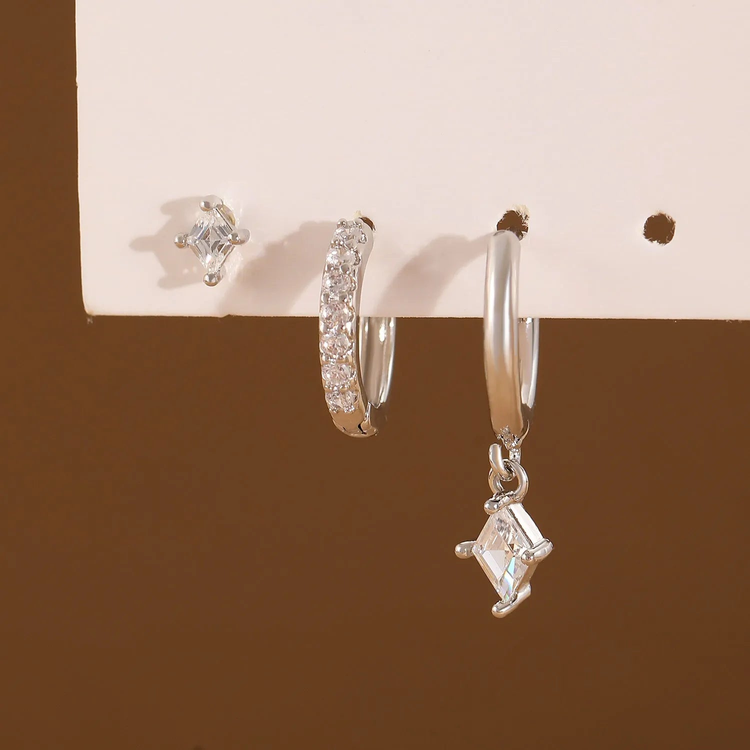 Gold and white geometric earring set with pendant, studs, and clasps featuring inlaid zircon.