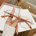 Women's gold alloy frame glasses with wood grain pattern and multiple coloured interchangeable lenses.