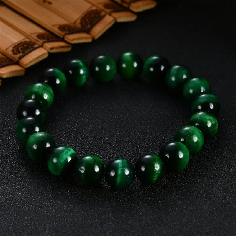 Green tiger eye stone bracelet with geometric polished beads on a wrist.