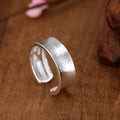 Geometric open ring in frosted sterling silver on a neutral background, showing adjustable opening.