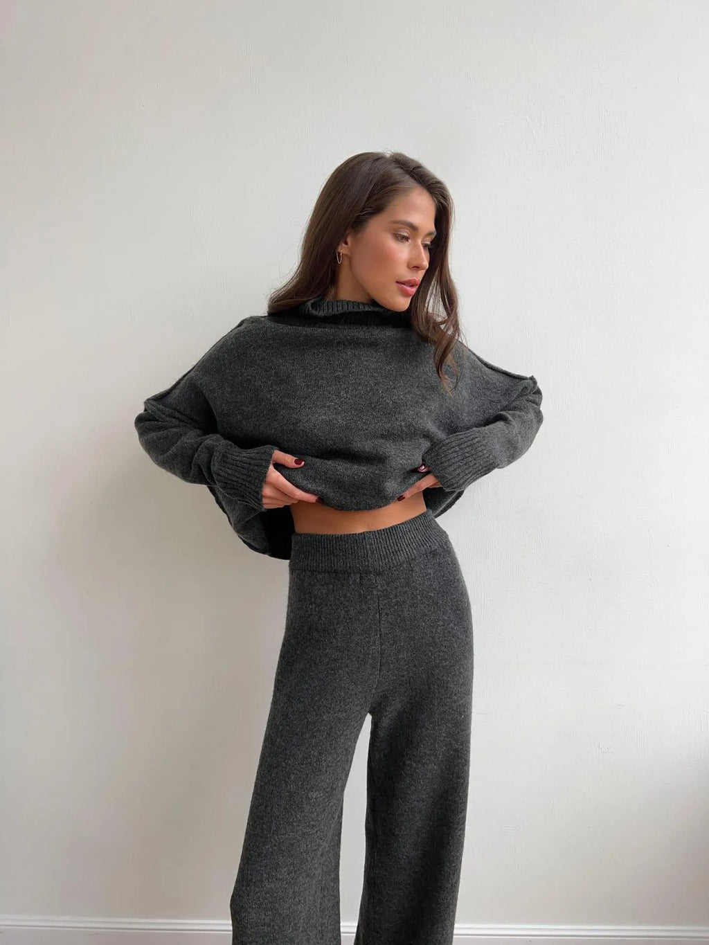Women's dark grey acrylic knitted sweater with side slits and matching trousers.