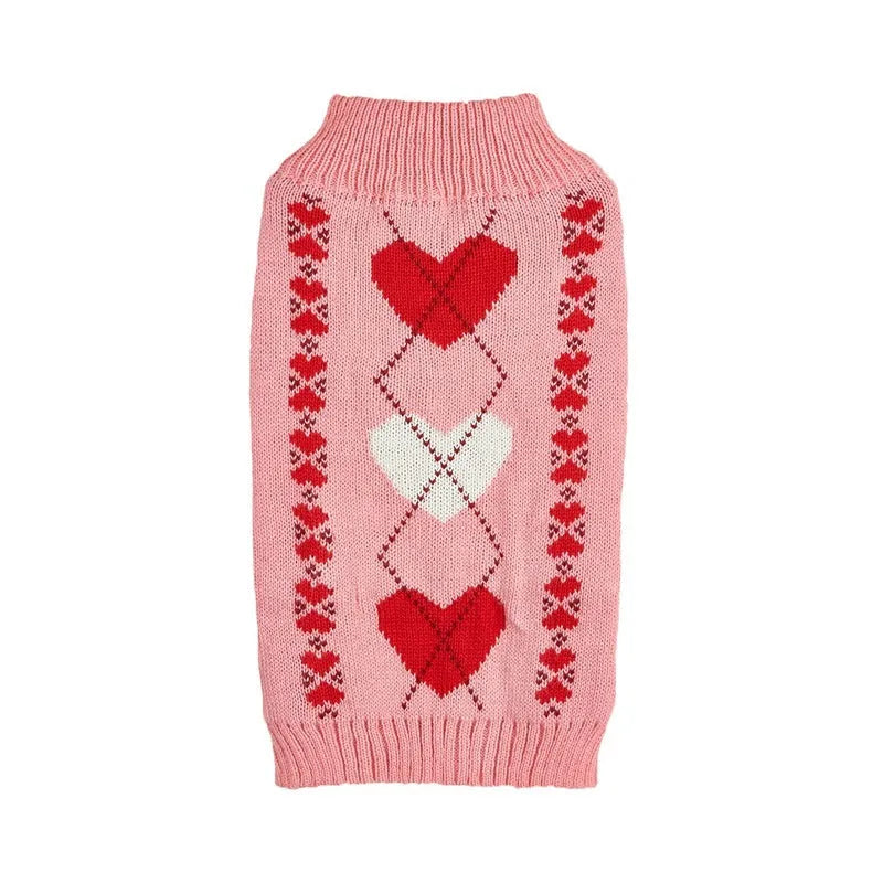 Small dog wearing a red knitted jumper with a white love heart motif on the chest.