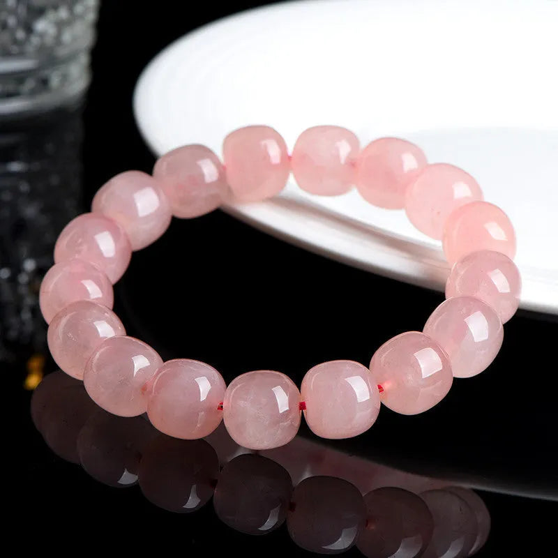 Pink natural crystal bracelet with polished geometric barrel-shaped beads on a wrist.