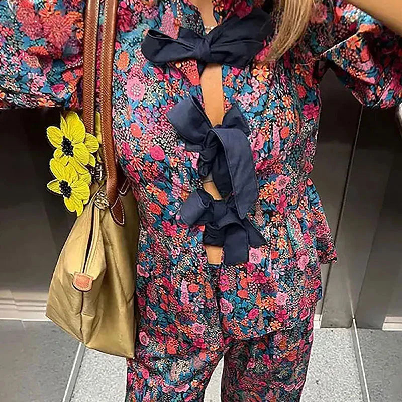 Women's floral print trouser suit with tie-neck blouse featuring puff sleeves