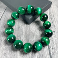 Green tiger eye stone bracelet with geometric polished beads on a wrist.