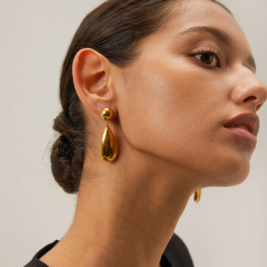 Gold electroplated stainless steel earrings with a geometric hemisphere and water drop pendant.