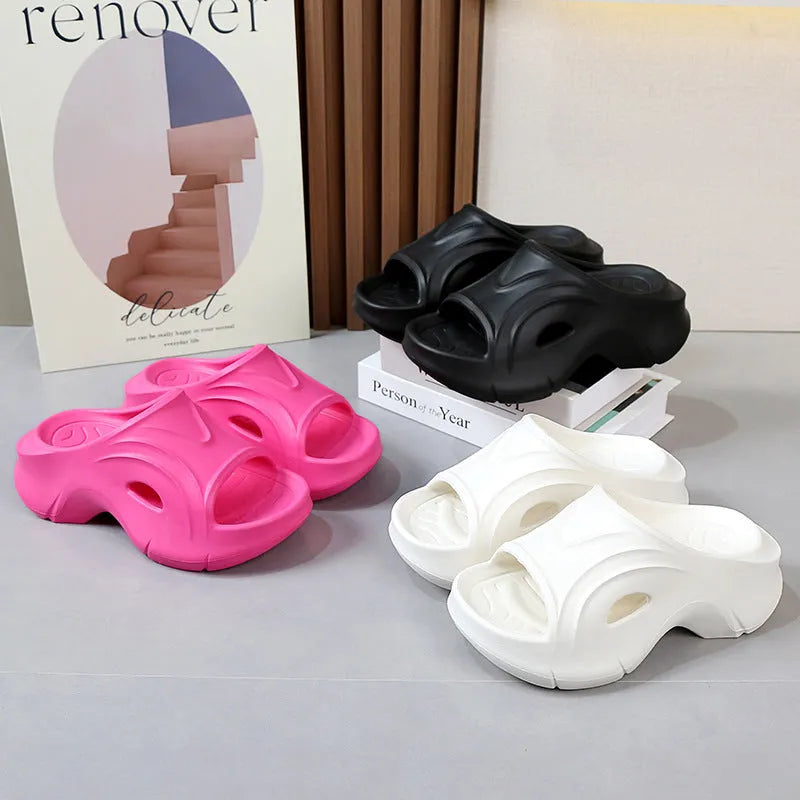 Women's white thick-soled EVA slippers with round toe on a sandy beach.