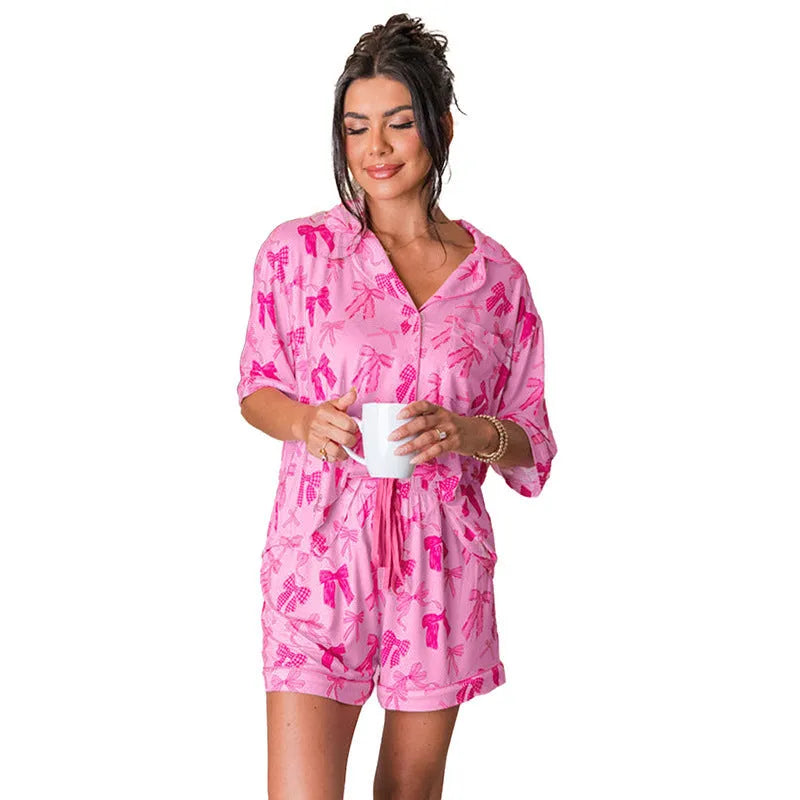 Pink polyester pyjama set with bow print, showing top and pants for sleepwear.