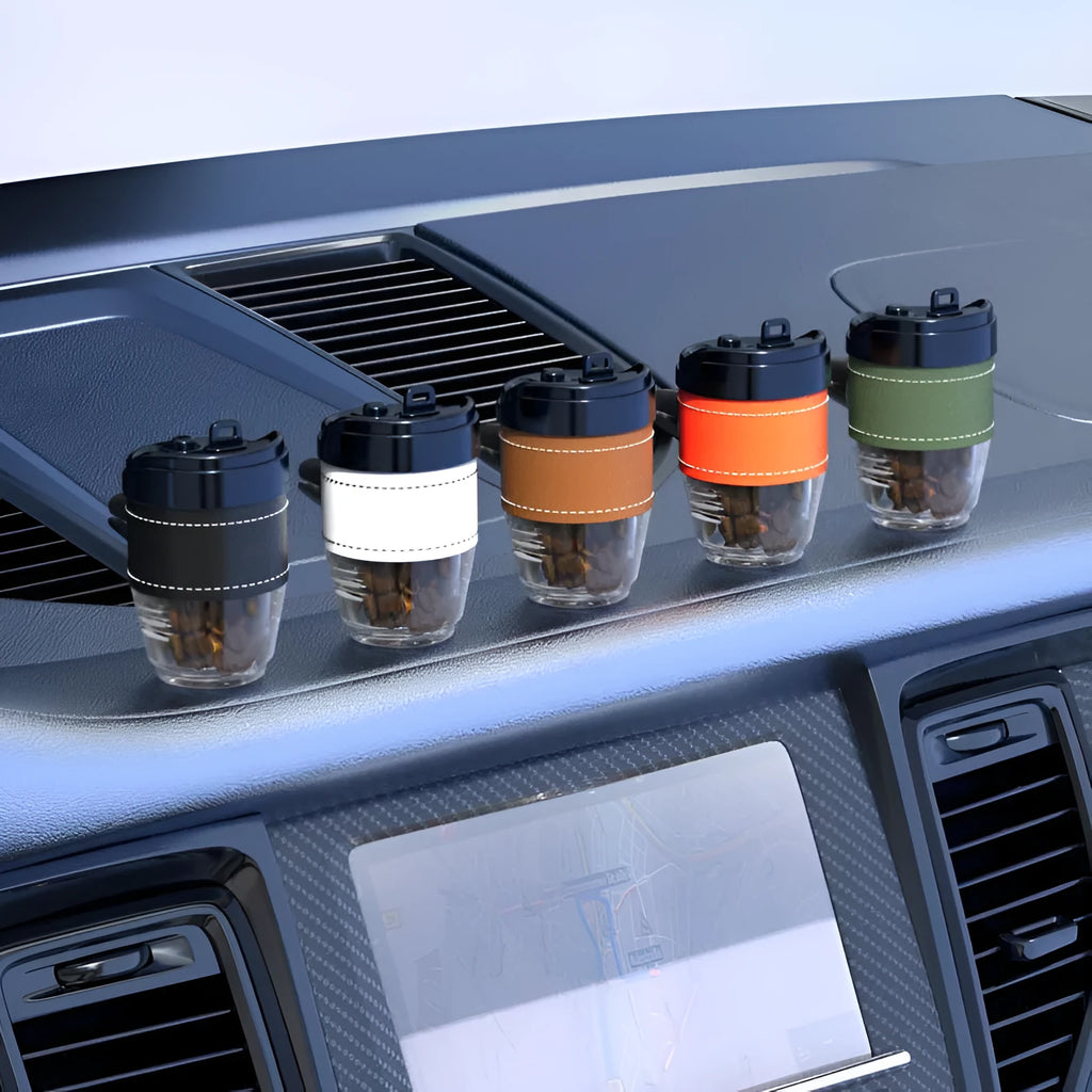 Coffee cup shaped plastic car air freshener in various colours on a car dashboard.