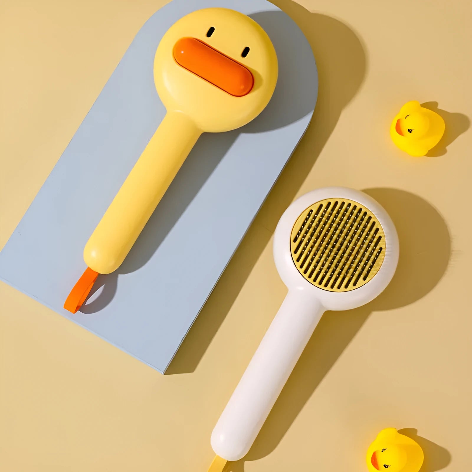 Yellow duck-shaped pet comb with open-section design and floating needle teeth for cat and dog grooming