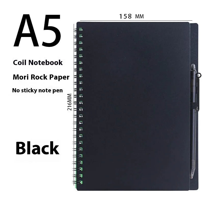 Open erasable coil notebook with stone paper pages, a pen, and a wipe cloth on a desk.