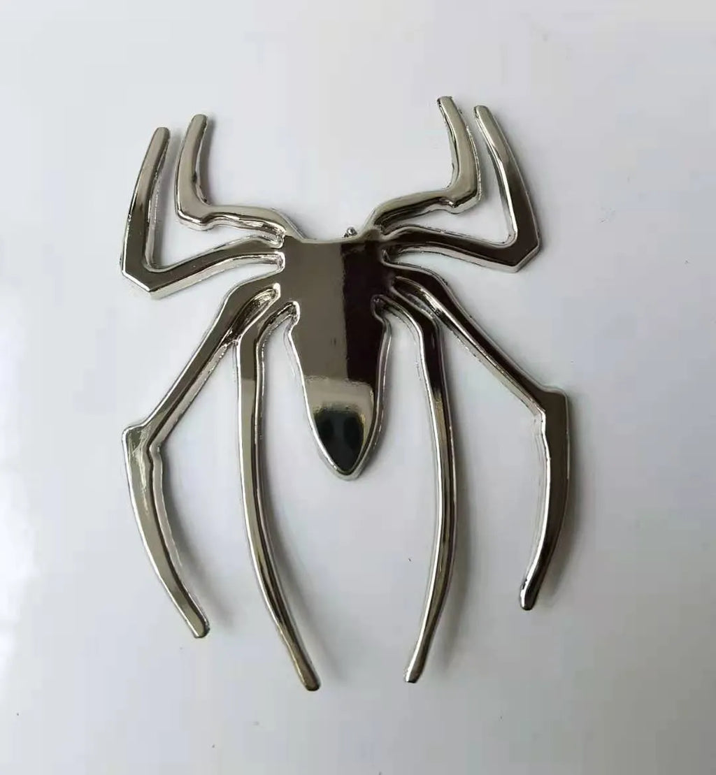 Three-dimensional metal spider bumper sticker in silver finish, measuring 7cm by 5cm.