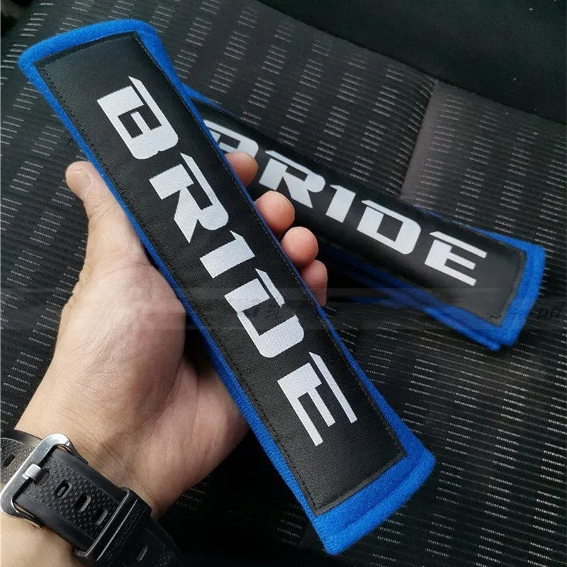 Pair of black car seatbelt shoulder pads made from cotton sponge cloth, showing embroidery detail.