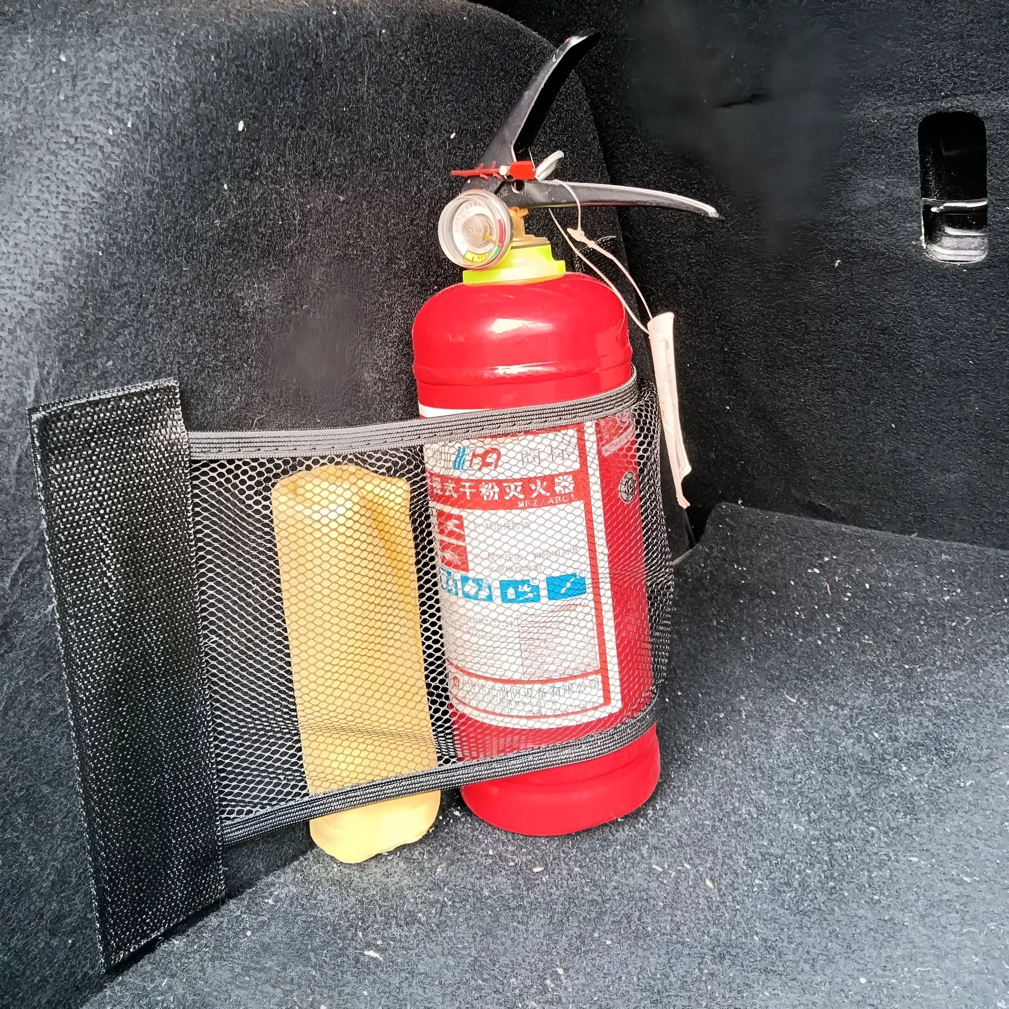 Elasticated grey polyester storage net stretched across a car boot, holding assorted items.