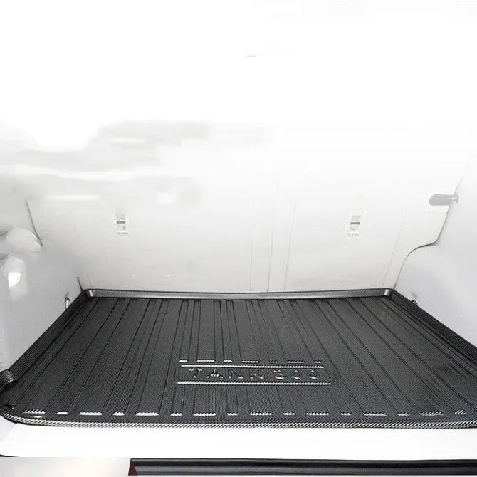 Black carbon fibre pattern TPE car boot liner mat fitted in a hatchback trunk.
