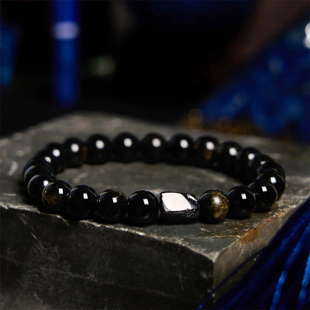 Natural obsidian single ring 8mm beaded bracelet in gold obsidian style on a plain background