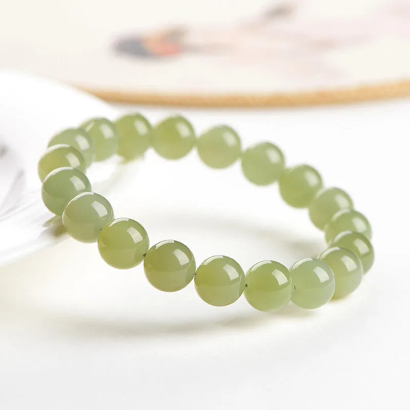 Polished Hetian jade ball bracelet with ice-like translucent beads in spherical shapes on a plain background