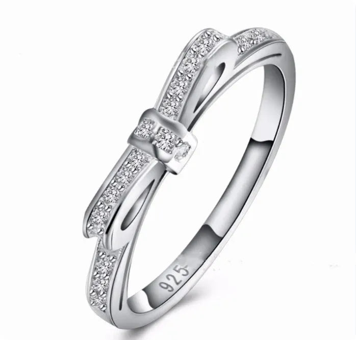 Silver bow-shaped ring with crystal zircon and rhinestone detailing on a finger