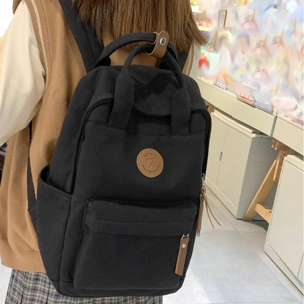 Solid black Oxford cloth fashion backpack with retro sewing thread details and curved shoulder strap for school and travel.