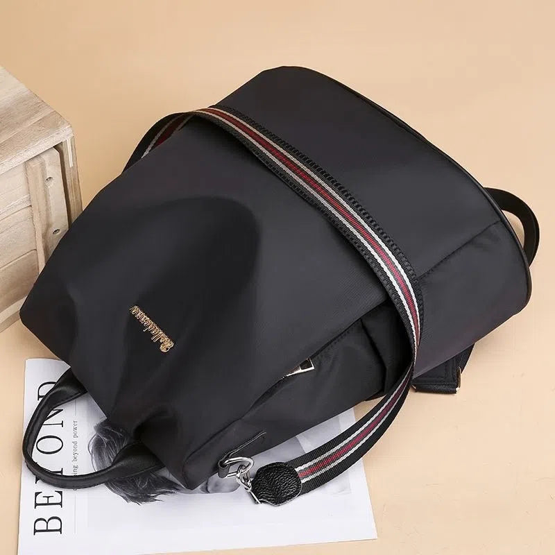 Women's large capacity black backpack with Oxford fabric lining, laptop sleeve, and trendy stitched seams and colour blocking