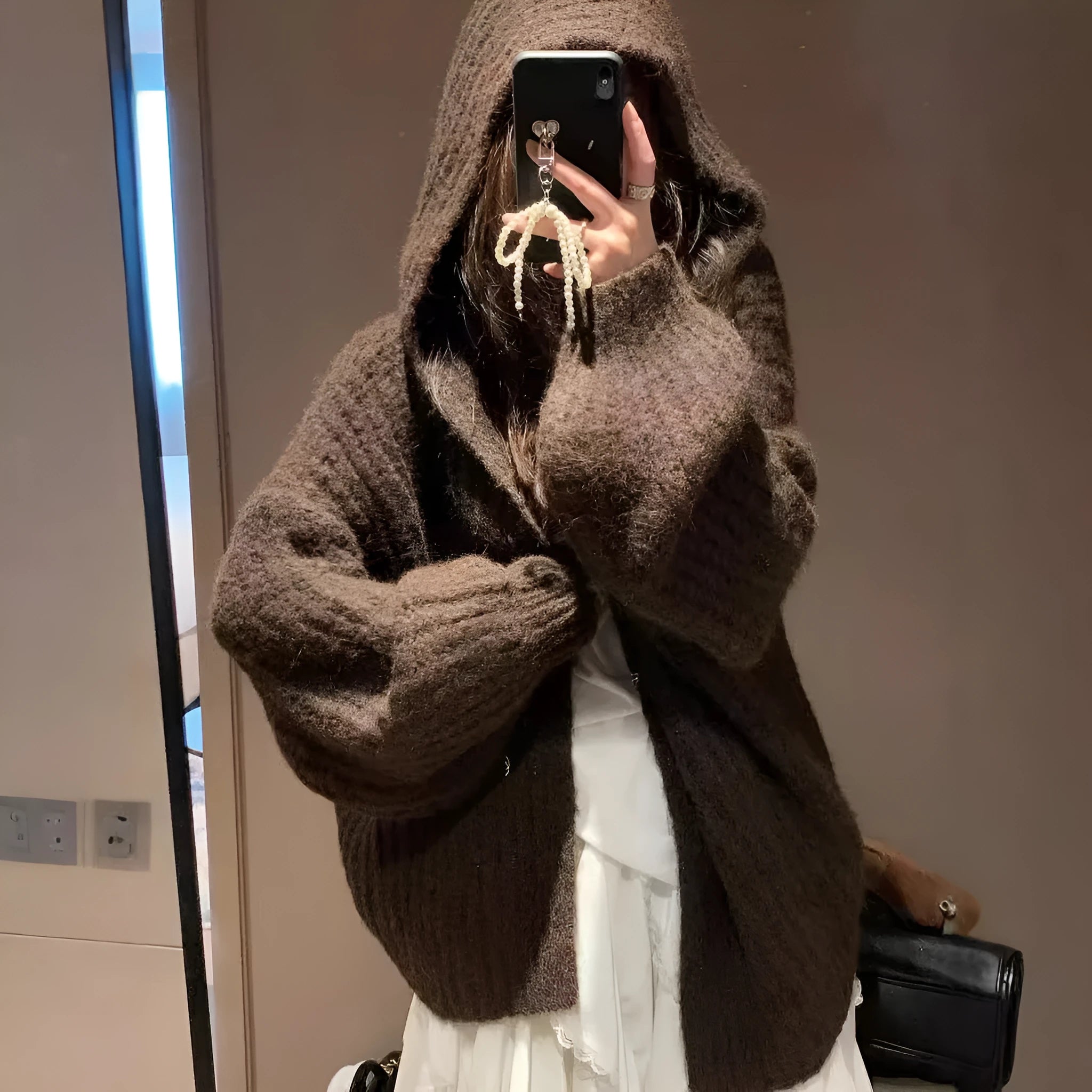 A woman wearing a thick, dark grey hooded cardigan with a loose fit and regular sleeves.