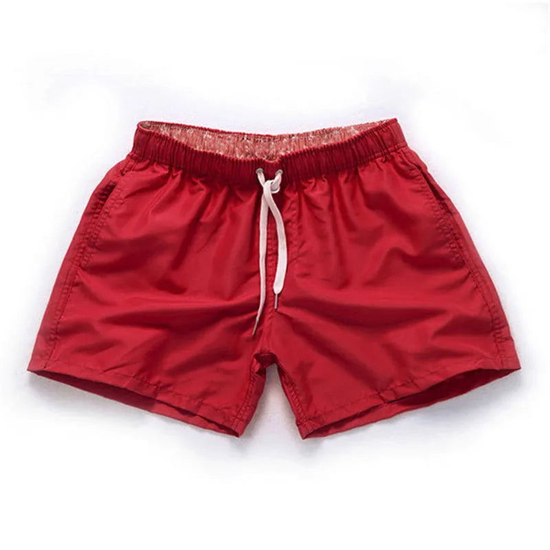 Men's polyester straight-leg surf shorts on a hanger, available in multiple solid colours.