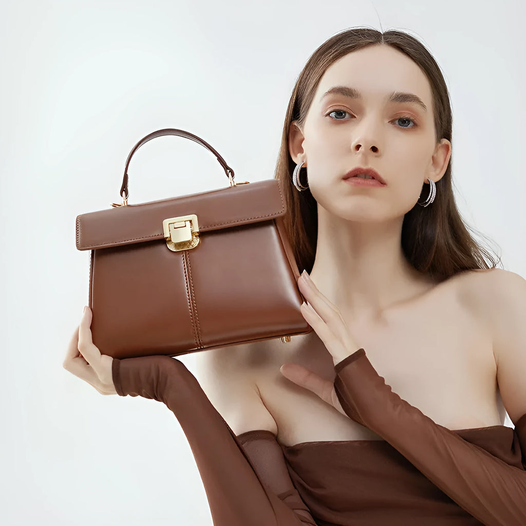 Black leather women's shoulder bag with vachette clasp showing square shape and adjustable strap.