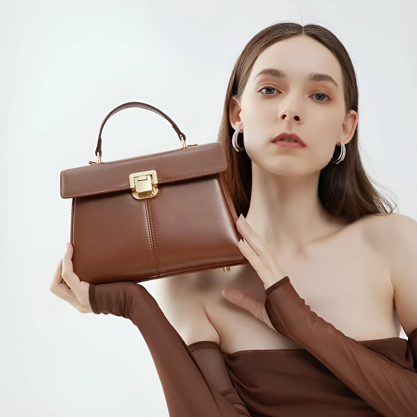 Black leather women's shoulder bag with vachette clasp showing square shape and adjustable strap.