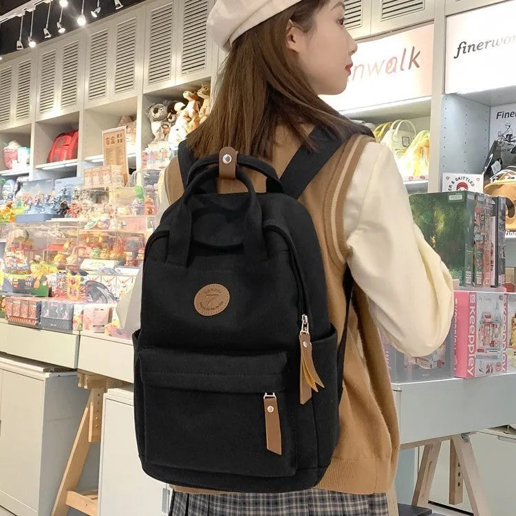 Solid black Oxford cloth fashion backpack with retro sewing thread details and curved shoulder strap for school and travel.